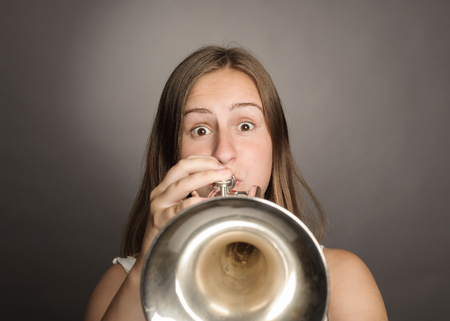 woman playing trumpet on a gray backgroundの写真素材