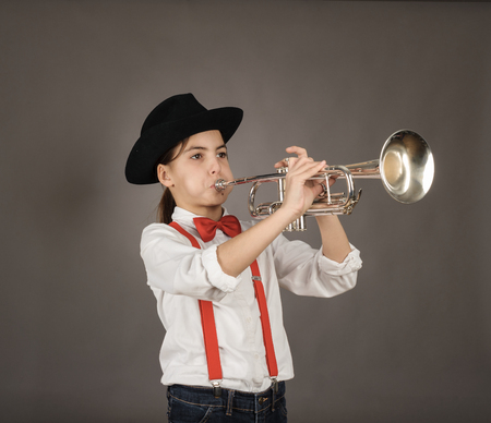 little girl playing trumpet on a gray backgroundの写真素材