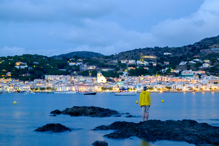 man looking at the small village of Port de la selva at sunsetの写真素材