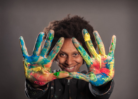 happy black woman with her hands painted on a gray backgroundの写真素材