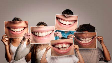 group of happy people holding a picture of a mouth smiling on a gray backgroundの写真素材