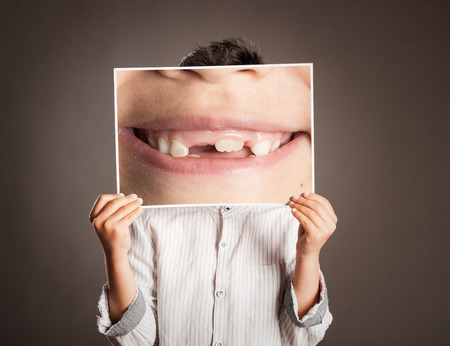 little boy holding a picture of a mouth smilingの写真素材