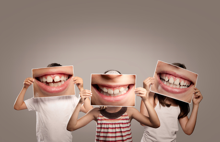 three children holding a picture of a mouth smilingの写真素材