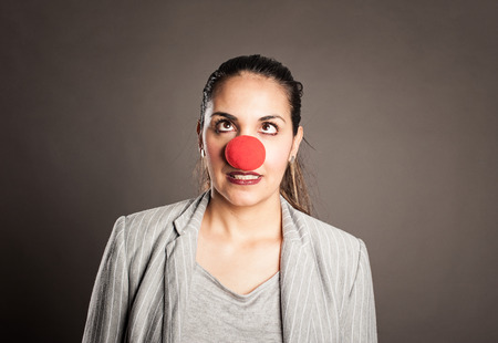 happy businesswoman with a clown nose on a gray backgroundの写真素材