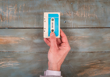 hand holding a cassette tape on wooden backgroundの写真素材