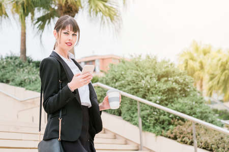 Portrait of beautiful business woman using smartphone on her way to workの写真素材