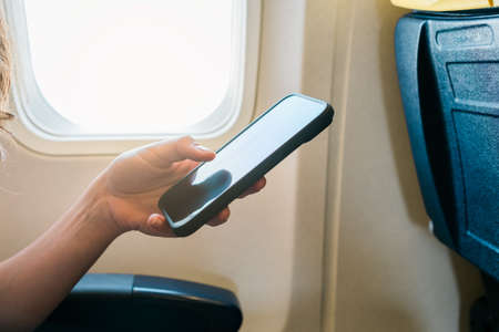 young girl hand using smartphone on airplane