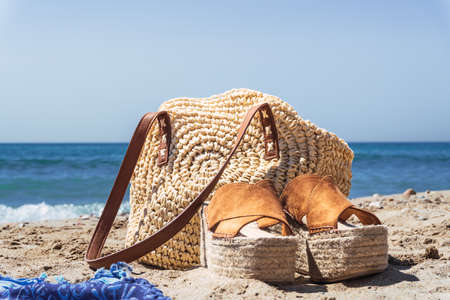 Close up shot of women's handbag and shoes on the beach with blurred backgroundの写真素材
