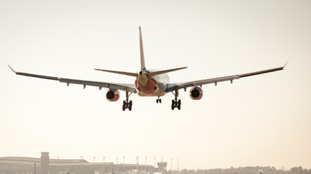 Red-white airplane landing during sunset on Barcelona airport runway. Fuselage and landing gear. Aircraft enginesの写真素材