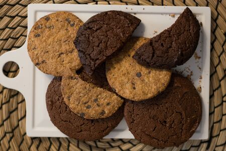 An overhead view of homemade chocolate biscuits and oatmeal cookies with chocolate bits on a trayの写真素材