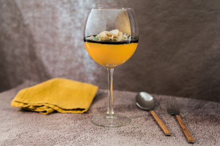 Cuttlefish tagliatelle, pumpkin puree and ink sauce served in a glass beside cutlery and a napkin on gray backgroundの写真素材