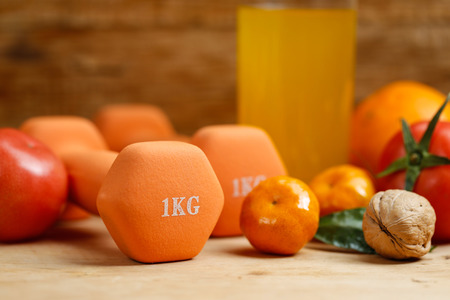 Dumbbell, orange juice, fruit and nuts on the wooden table, sport and health lifestyle conceptの写真素材