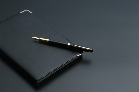 golden pen,notebook,calculator and glasses on black deskの写真素材