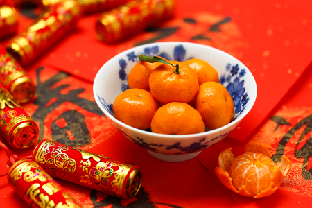 Chinese new year oranges in bowl and fake firecrackers on spring festival  couplets that says happiness and spring is comingの写真素材