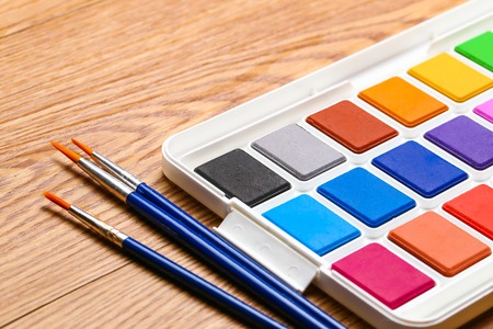 Set of solid watercolors and paintbrush on wooden table backgroundの写真素材