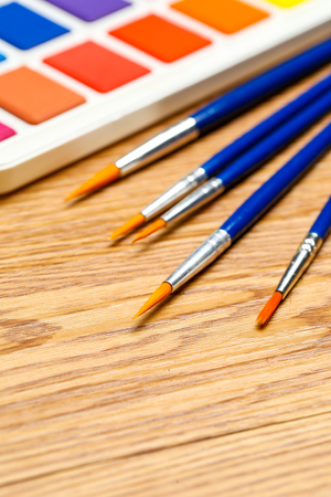 Set of solid watercolors and paintbrush on wooden table backgroundの写真素材