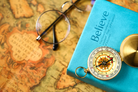 close up view of Compass and book on vintage old map paper backgroundの写真素材