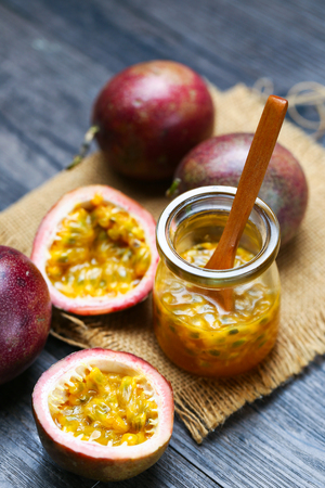 Fresh passion fruit juice in glass bottle and wooden spoon on dark wooden table.の写真素材