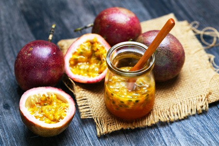 Fresh passion fruit juice in glass bottle and wooden spoon on dark wooden table.の写真素材