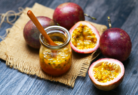Fresh passion fruit juice in glass bottle and wooden spoon on dark wooden table.の写真素材