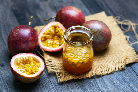 Fresh passion fruit juice in glass bottle on dark wooden table.の写真素材
