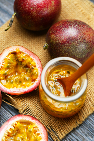 Fresh passion fruit juice in glass bottle and wooden spoon on dark wooden table.の写真素材