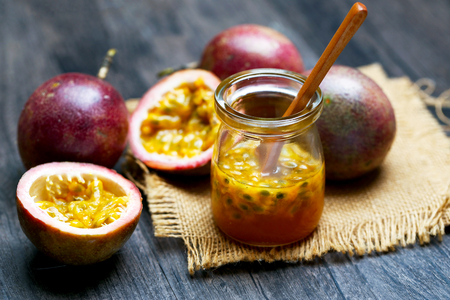 Fresh passion fruit juice in glass bottle and wooden spoon on dark wooden table.の写真素材