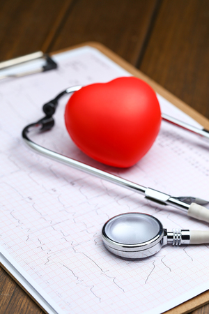 Red heart with stethoscope and electrocardiogram on wooden backgroundの写真素材