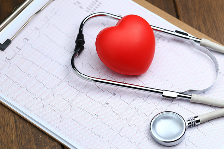 Red heart with stethoscope and electrocardiogram on wooden backgroundの写真素材