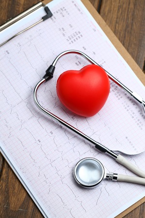 Red heart with stethoscope and electrocardiogram on wooden backgroundの写真素材