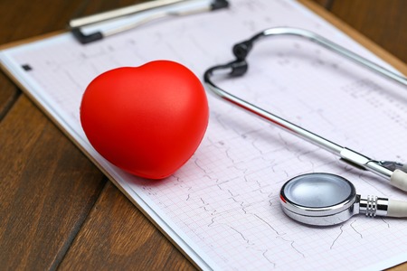 Red heart with stethoscope and electrocardiogram on wooden backgroundの写真素材