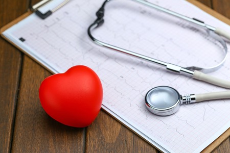 Red heart with stethoscope and electrocardiogram on wooden backgroundの写真素材