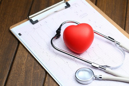 Red heart with stethoscope and electrocardiogram on wooden backgroundの写真素材