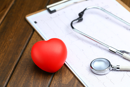 Red heart with stethoscope and electrocardiogram on wooden backgroundの写真素材