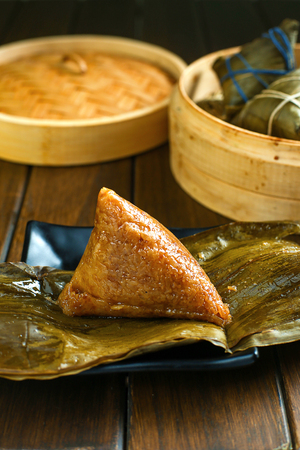 rice dumplings (zongzi) and bamboo steamer on wooden tableの写真素材