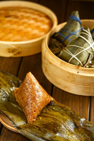 rice dumplings (zongzi) and bamboo steamer on wooden tableの写真素材