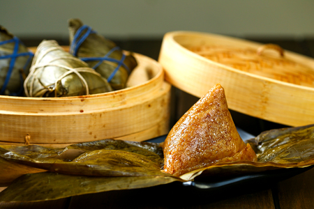 rice dumplings (zongzi) and bamboo steamer on wooden tableの写真素材