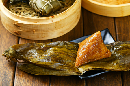 rice dumplings (zongzi) and bamboo steamer on wooden tableの写真素材