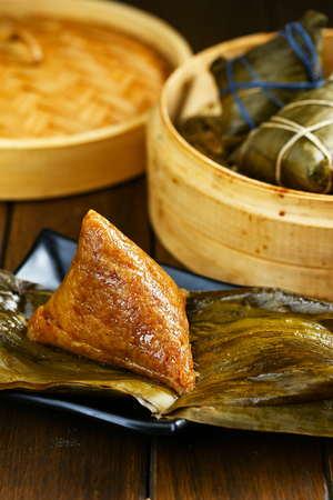 rice dumplings (zongzi) and bamboo steamer on wooden tableの写真素材