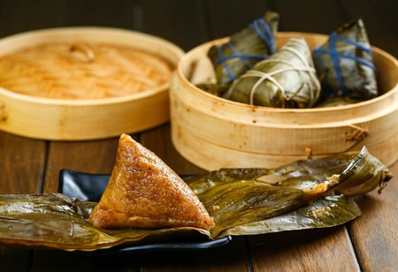 rice dumplings (zongzi) and bamboo steamer on wooden tableの写真素材