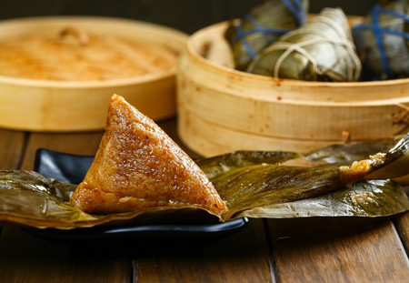 rice dumplings (zongzi) and bamboo steamer on wooden tableの写真素材