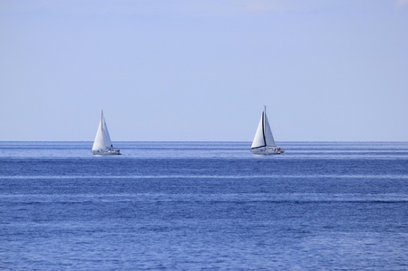 Two sailboats on open blue sea horizonの写真素材