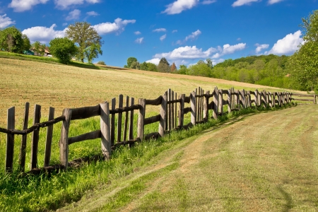 Wooden fence in green landscape under blue skyの写真素材