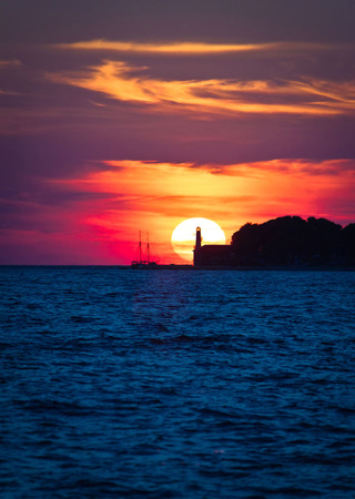 Sailboat and lighthouse on dramatic sunset in Zadar, Dalmatia, Croatiaの写真素材