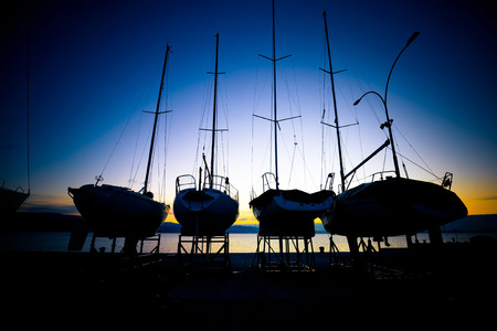 Sailboats at dry dock sunrise silhouette view in marinaの写真素材
