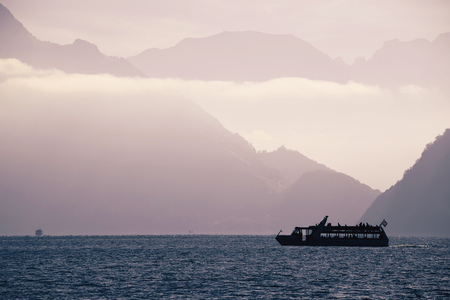 Boat on Swiss alke Luzern with mountain cliffs background silhouette view, central Switzerland