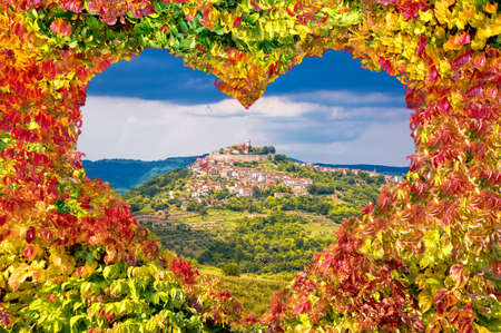 Historic town of Motovun on green hill view through heart shaped autumn leaves, Istria region of Croatiaの写真素材