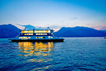Ferry boat on Como lake sunset view, Varenna in Lombardy, region of Italy