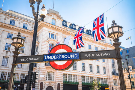 London Tube entrance sign and UK flags street view, capital of United Kingdomのeditorial素材