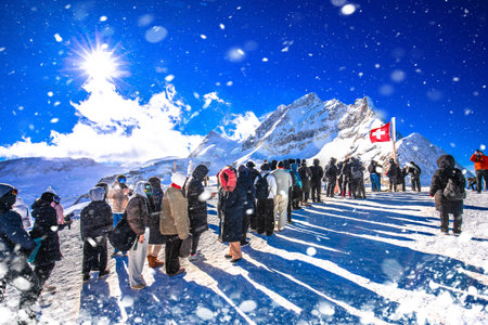 Tourists waiting in line to take a photo in front of Swiss flag on Jungfraujoch peak, Berner Oberland region of Switzerlandの写真素材